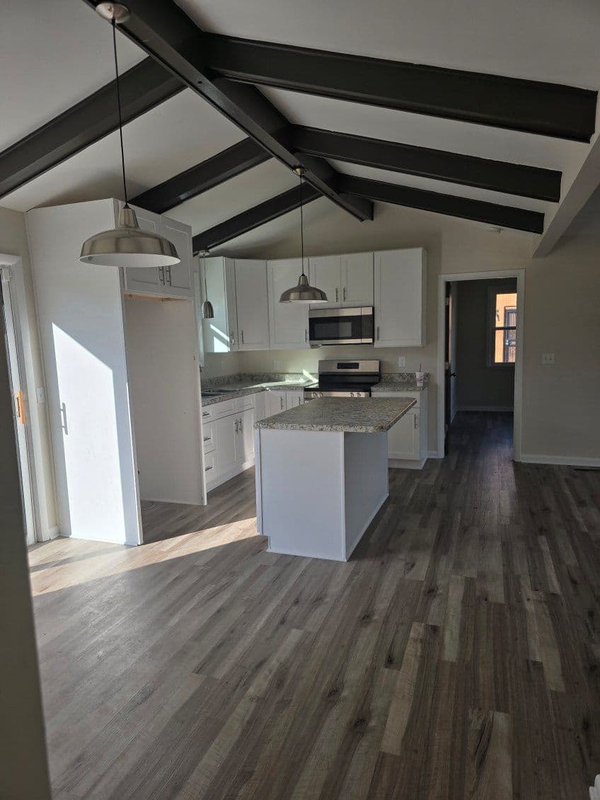 Modern kitchen with white cabinets, granite countertops, and vaulted ceilings. Bright, airy space.