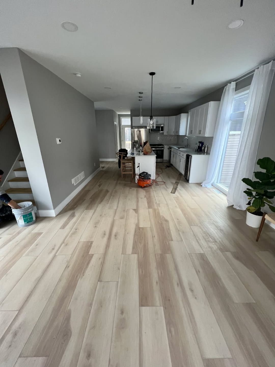 Modern open-concept kitchen and living area with light wood flooring and white cabinetry.