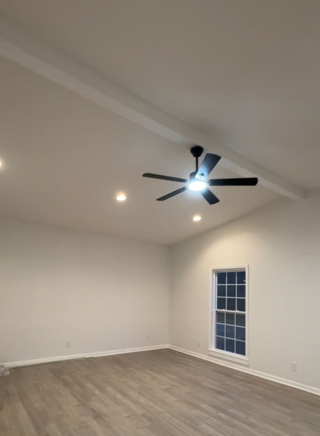 Bright, spacious room with a ceiling fan, recessed lighting, and large window.