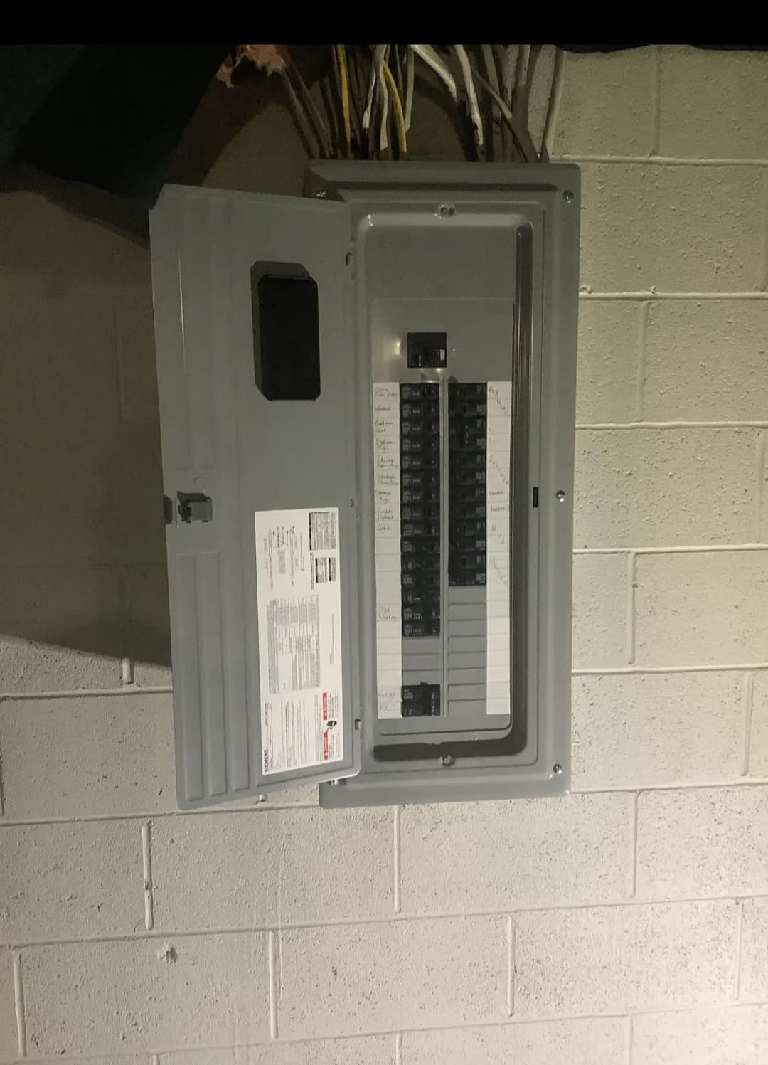 Electrical panel mounted on a concrete wall with circuit breaker switches visible.