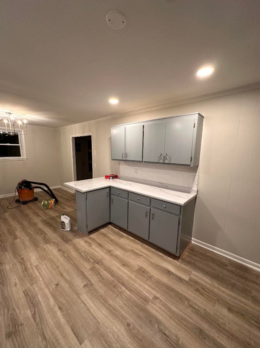 Modern kitchen with gray cabinets, white countertops, and laminate flooring. Bright lighting.