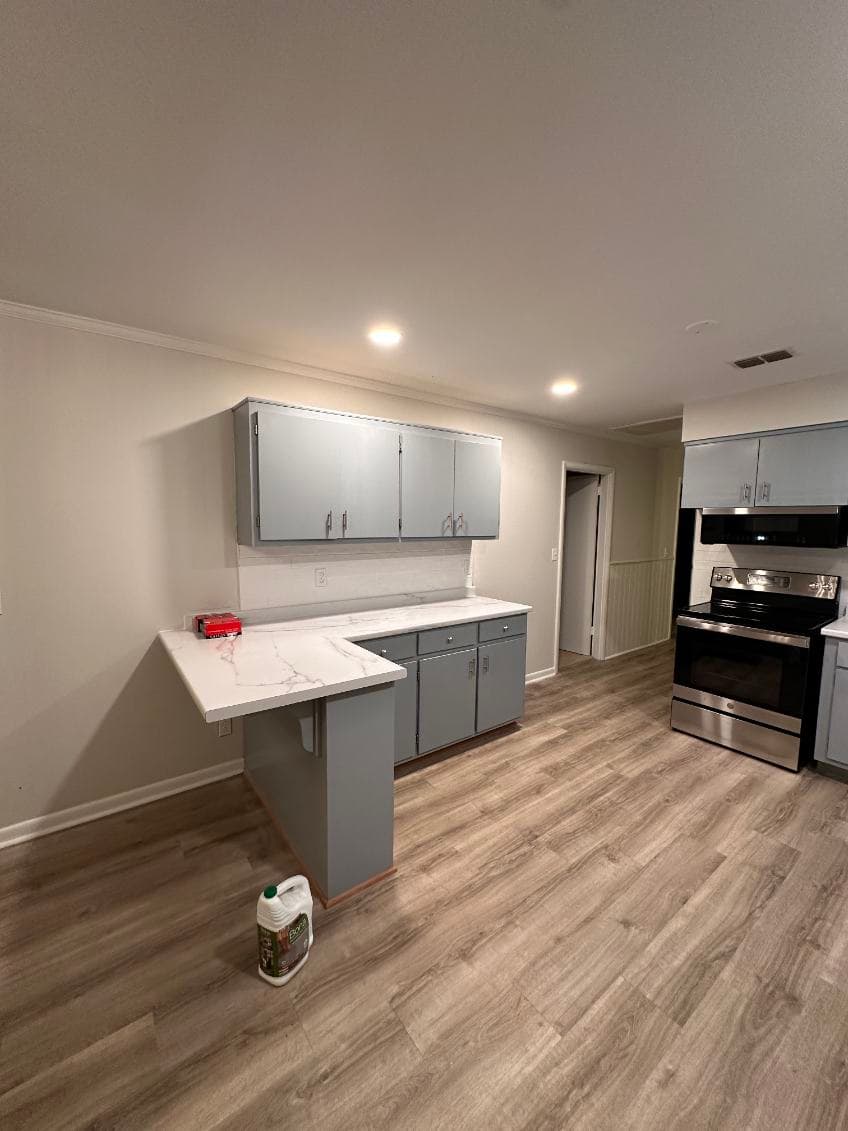 Modern kitchen with gray cabinets, marble countertop, and stainless steel appliances.