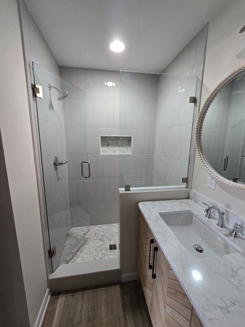 Modern bathroom with walk-in shower, gray tiles, and stylish vanity with sink.