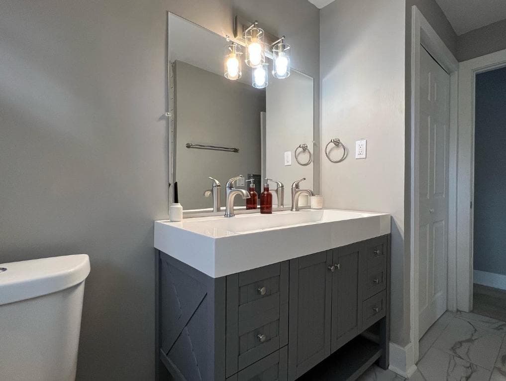 Modern bathroom featuring a double sink vanity, stylish lighting, and gray walls.