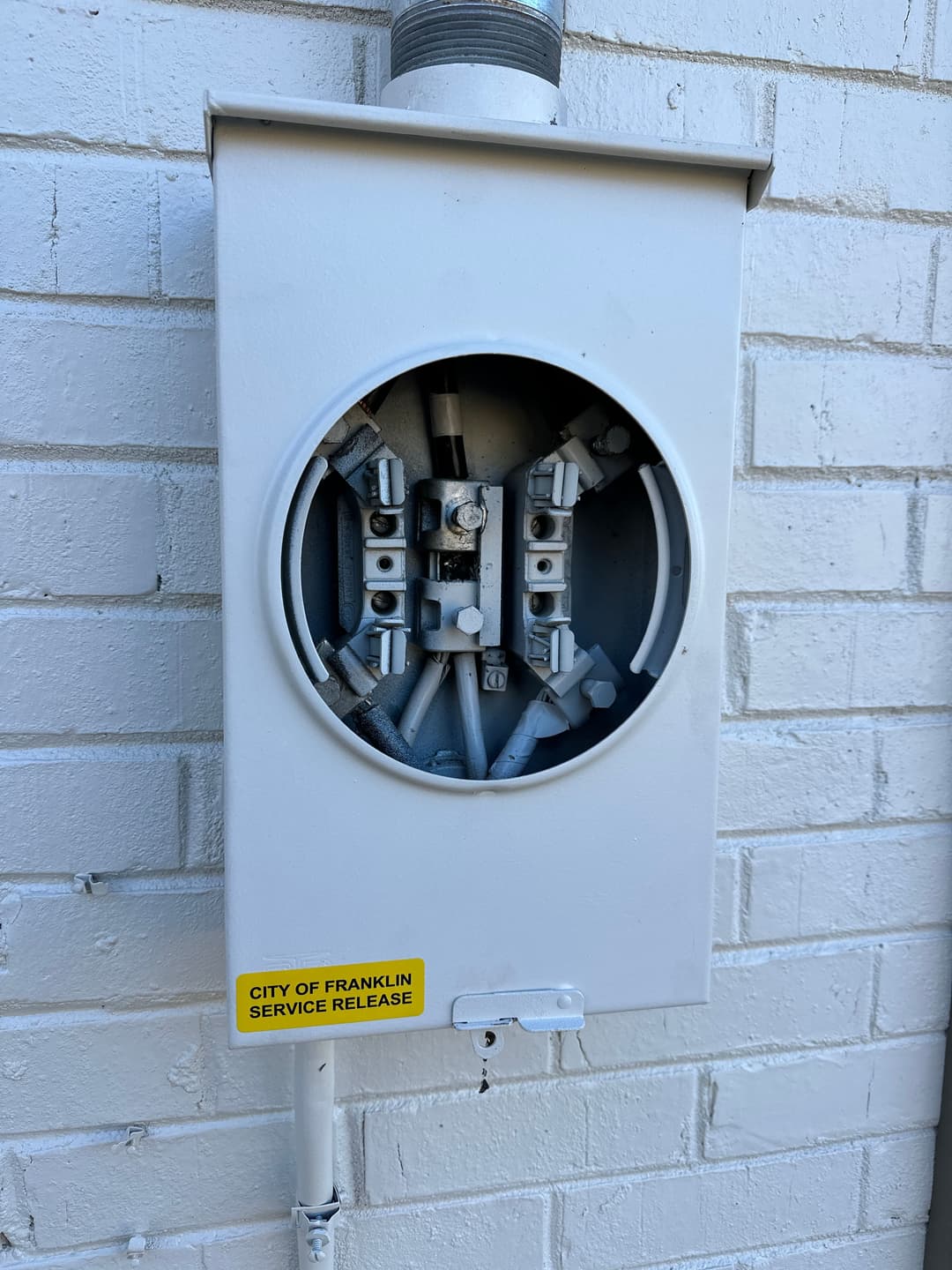 Utility meter on a white brick wall with a service release label.